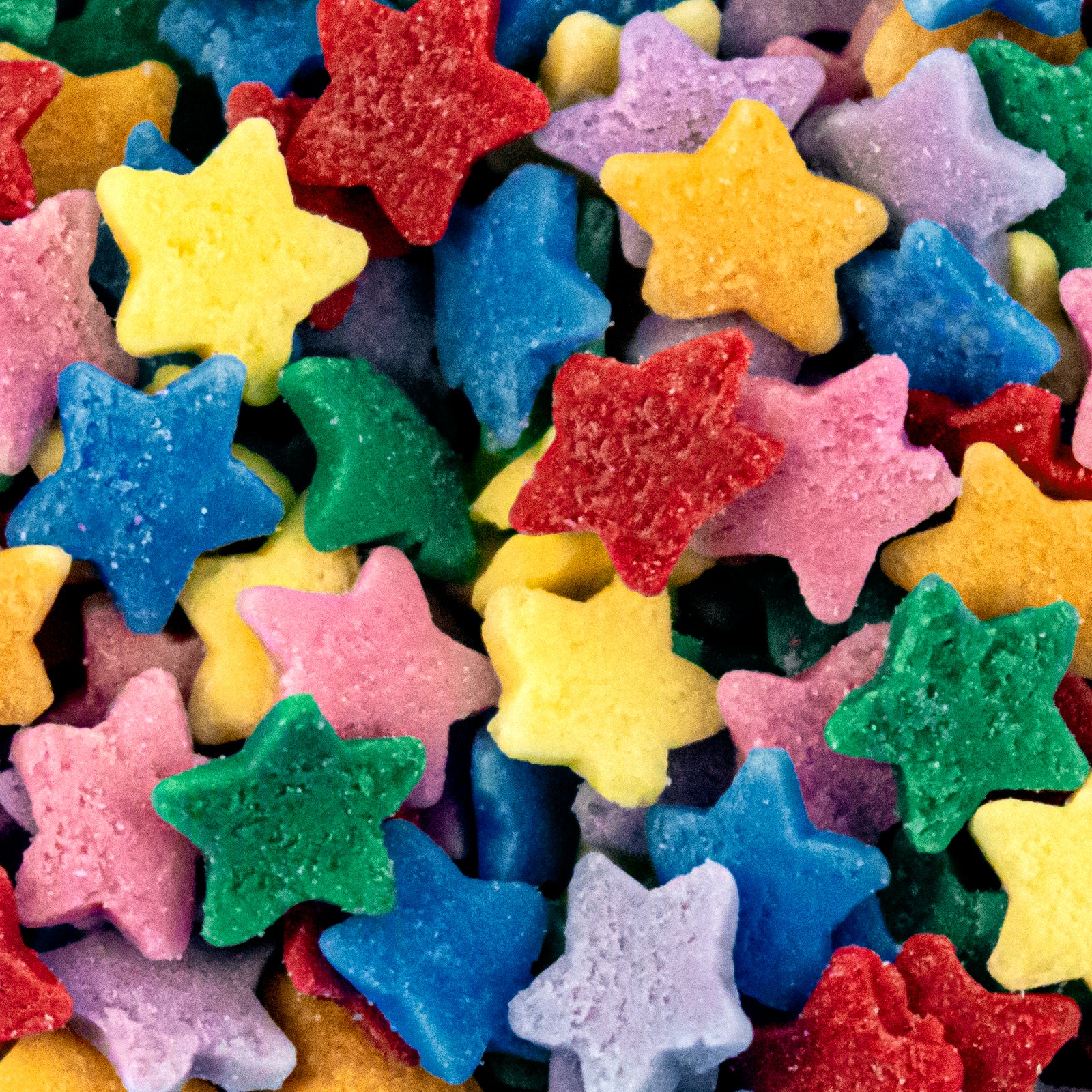 A close-up pile of small star-shaped sugar sprinkles in multiple bright colors, including yellow, blue, green, pink, purple, and red.
